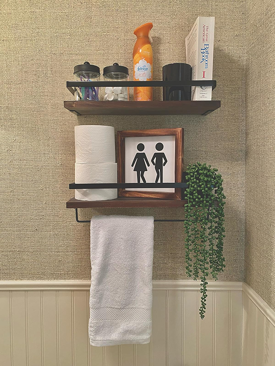 A decorated bathroom with beige linen wallpaper, a shelf with green hanging plant and storage jars for flossers and face wipes.